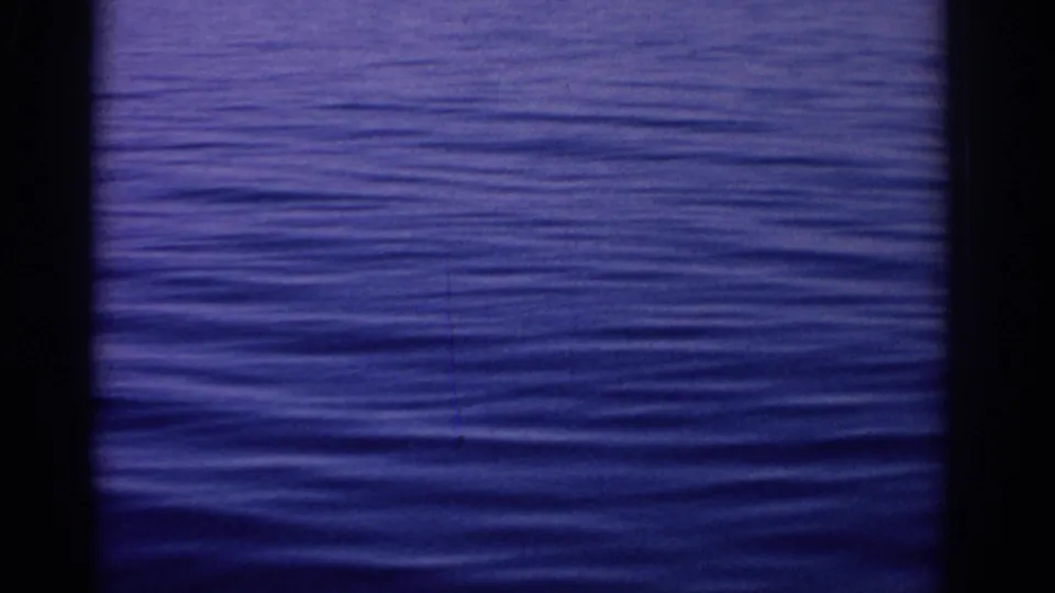 Archival 8mm view of blue rippling sea near Rhodes, with dark contact-sheet border and soft color shift.