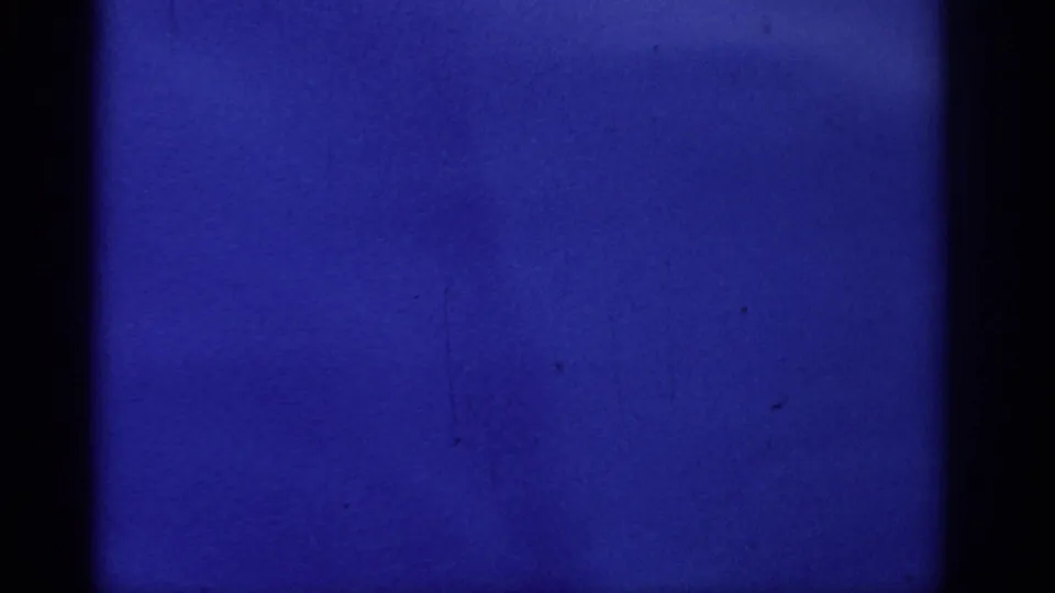 Blue 8mm ocean view from the Rhodes footage, showing calm water, dark film borders, and subtle archival texture.