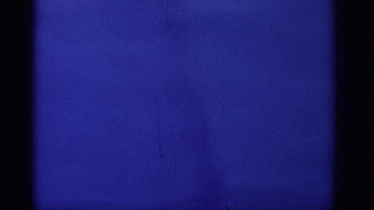 Mostly blue exposed film frame with dark vertical gate edges and faint film texture.