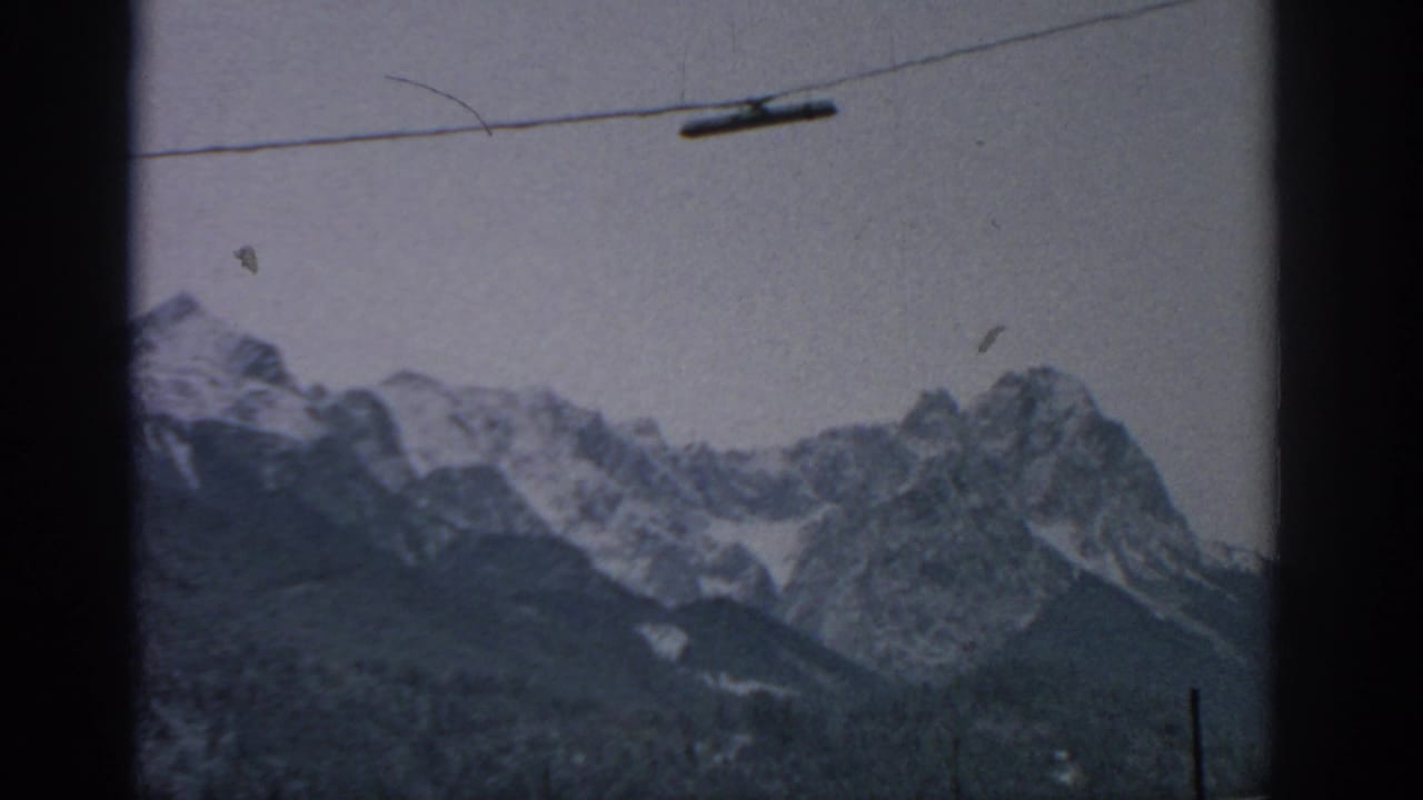 Mountain ridge and snow patches framed by a dark vertical window edge and cable line.