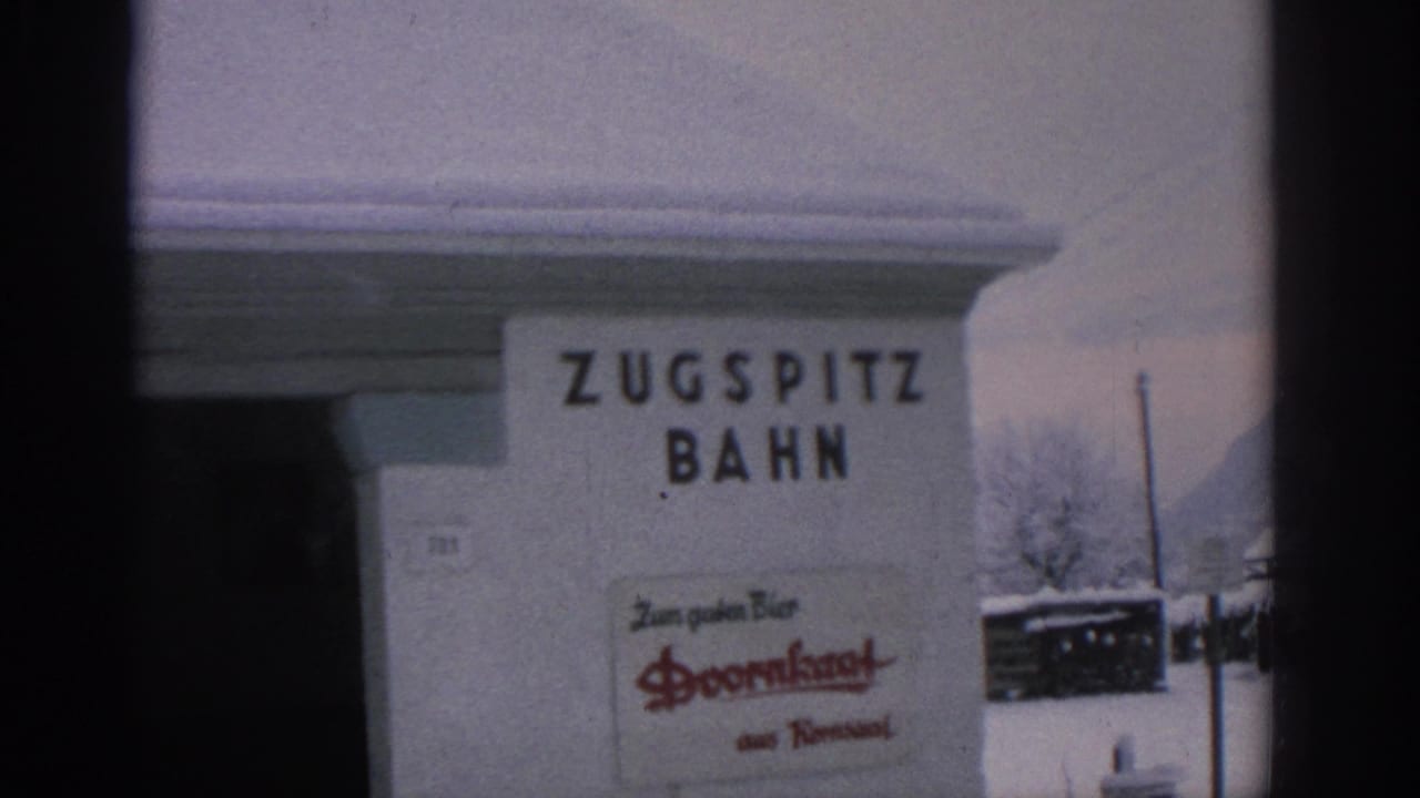 Snowy station wall with a Zugspitz Bahn sign and a Doornkaat advertisement.