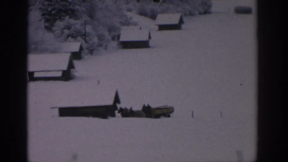 1963 German winter field with cabins and a small horse-drawn sled or cart crossing the snow.