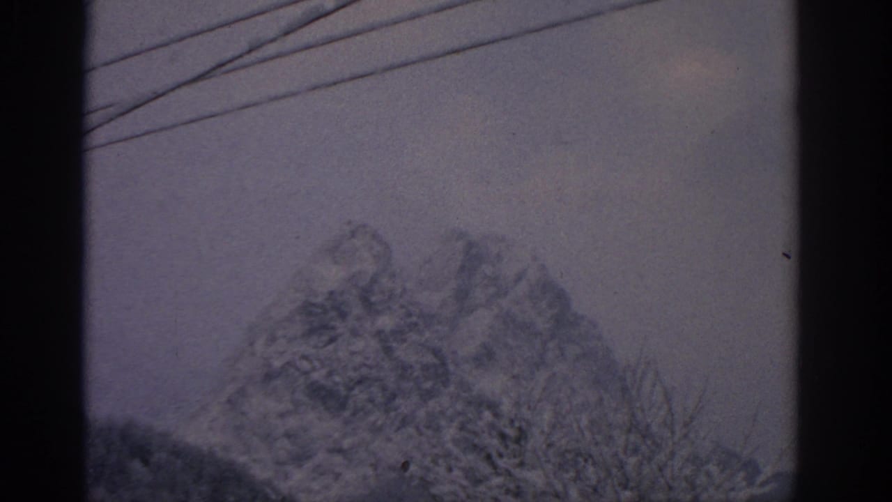 Distant snowy mountain framed by telephone wires and dark film borders.