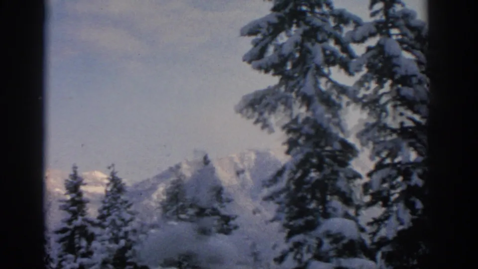 A distant snow-covered ridge is visible beyond evergreens in this 1963 8mm winter landscape near Munich.