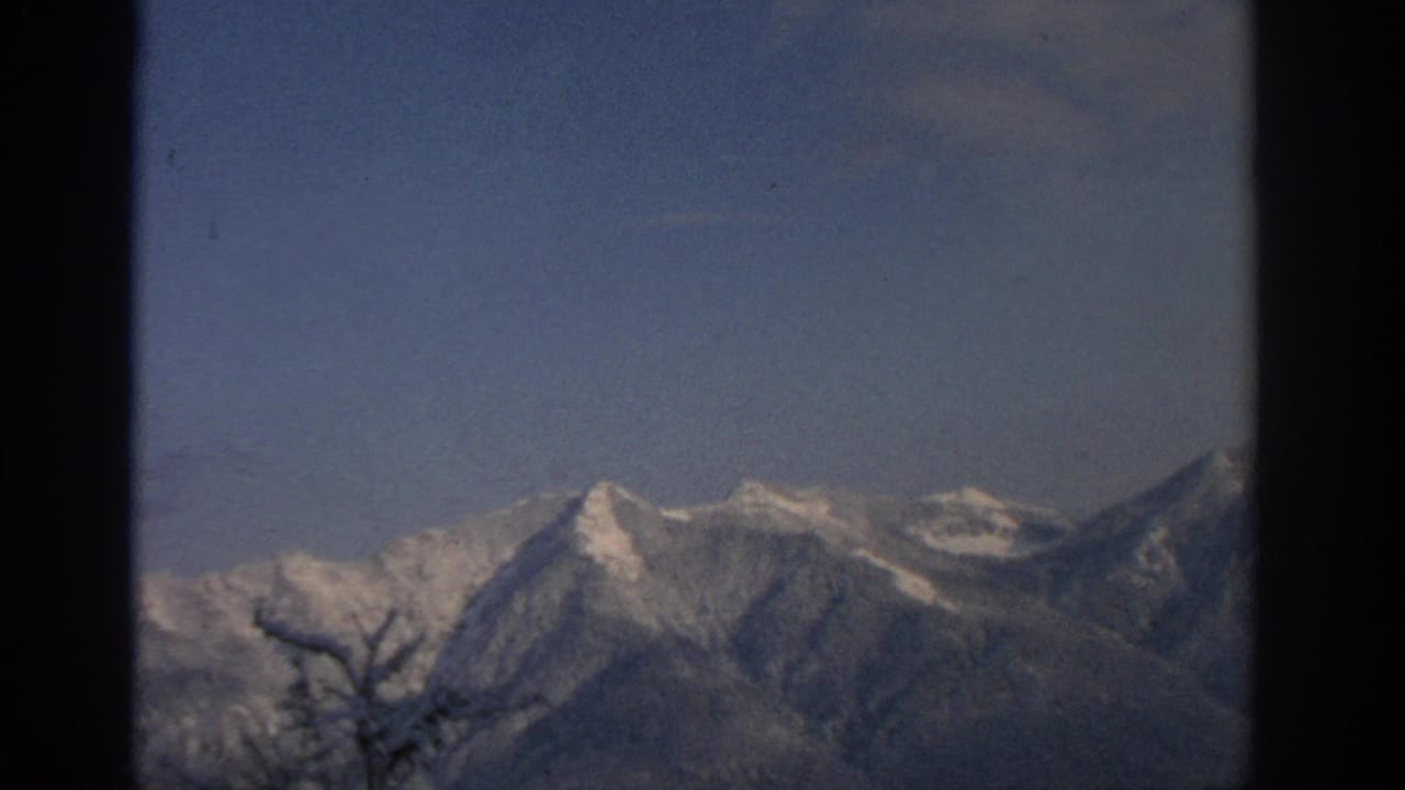 Snow-covered mountain peaks under a clear blue sky with dark frame edges.