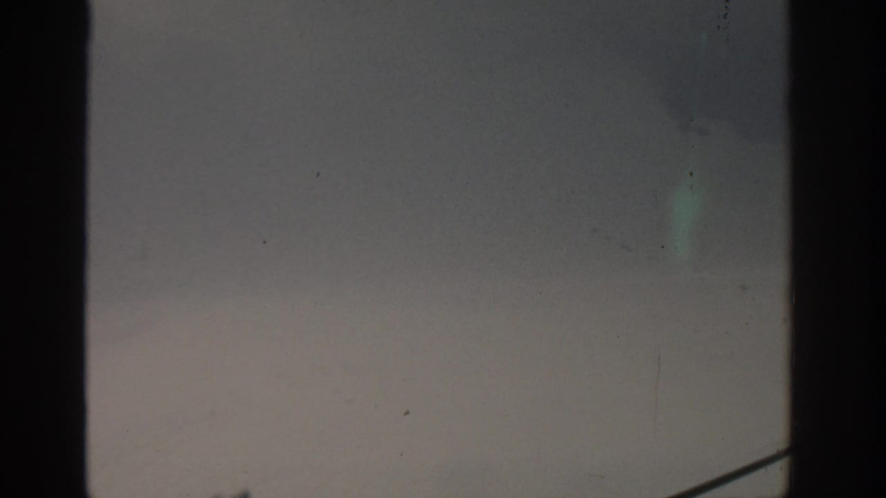 Gray sky with faint smoke and a diagonal railing line partly visible at the lower right.