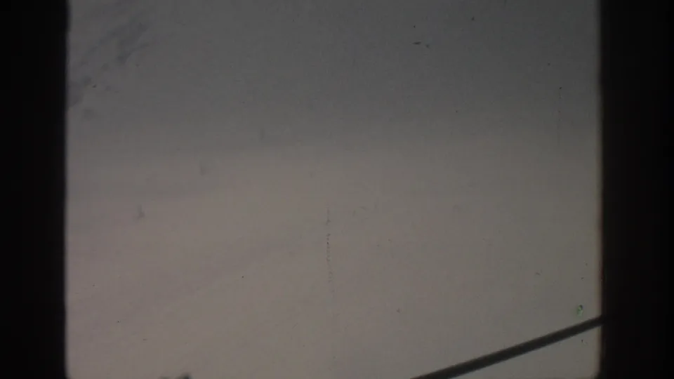 1963 Munich 8mm frame with gray sky, diagonal railing, film grain, and minor scratches near the frame edges.