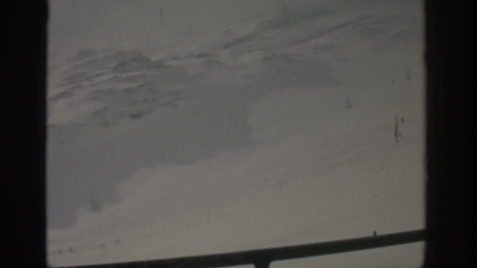 A grainy 1963 Munich window-view frame, divided by dark vertical framing with a pale gray exterior, faint texture, and a diagonal rail at the bottom.