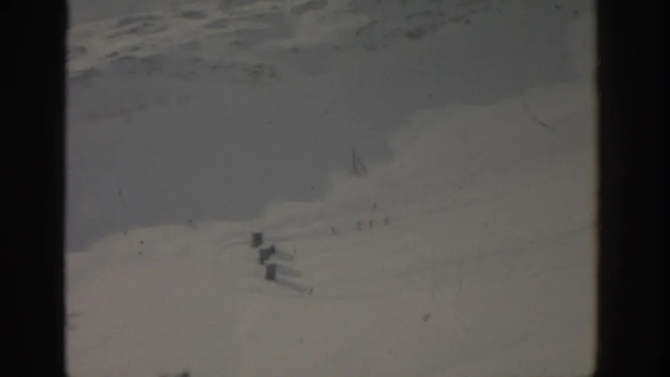 Distant 1963 winter slope near Munich with small ski-area structures, pale snow texture, and 8mm gate edges.