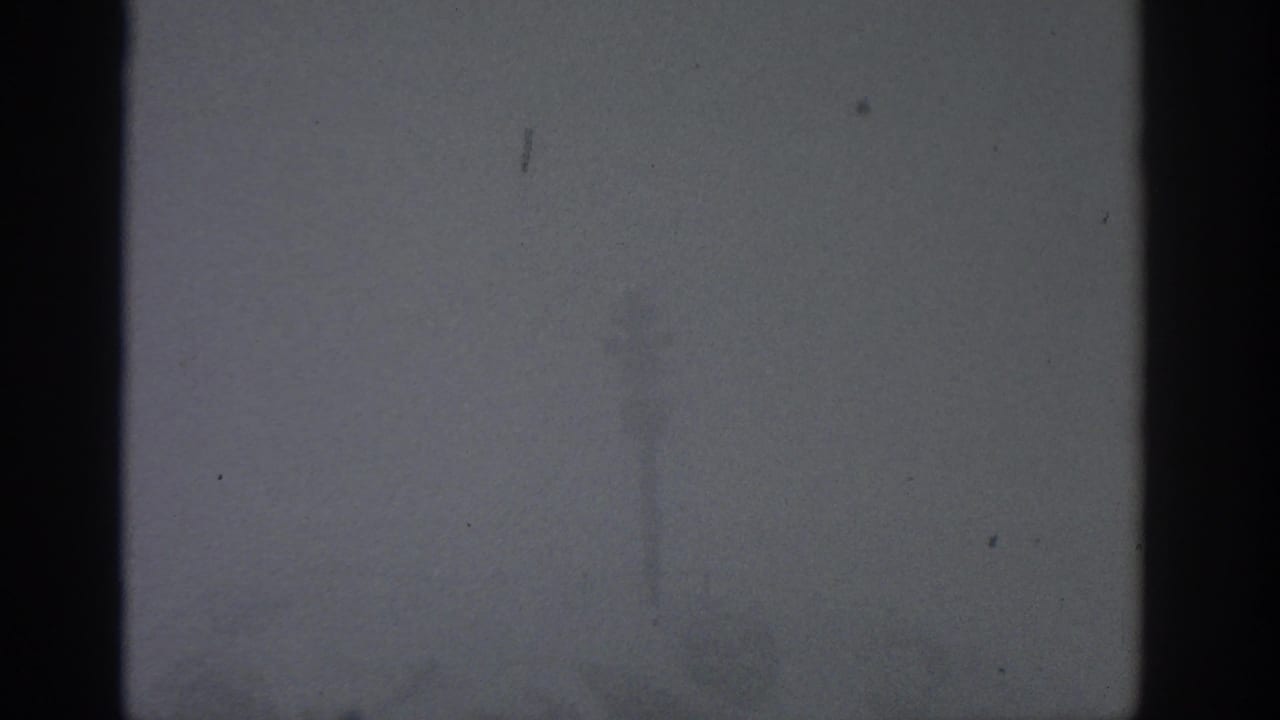 Foggy exterior with a dark central vertical pole and faint marks in the sky.
