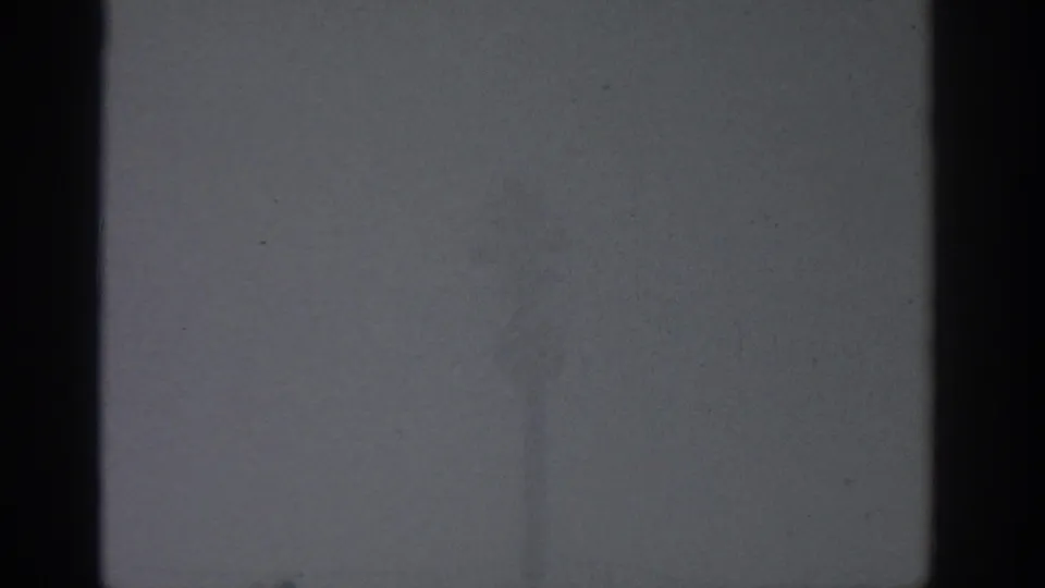 1963 Munich-attributed 8mm frame showing a gray foggy exterior with dark vertical borders and minimal detail.