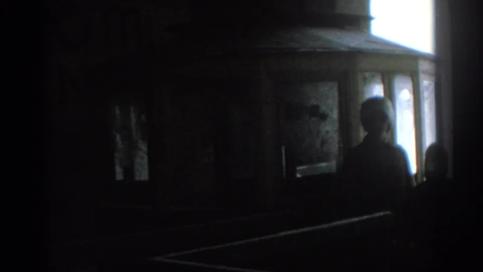 A silhouetted figure stands near the Munich tram cab windows, with another partial figure at the edge of frame.