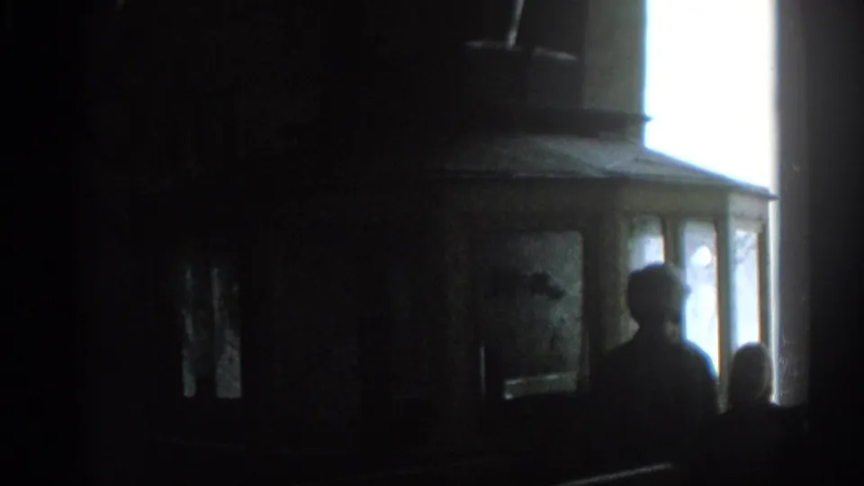 In Munich 1963 home-movie footage, silhouetted viewers appear against a bright screen or window inside a dim room.