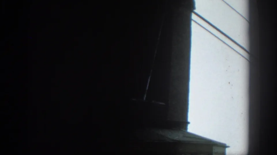 The frame shifts toward a bright surface with diagonal lines, with the viewing room mostly falling into shadow.
