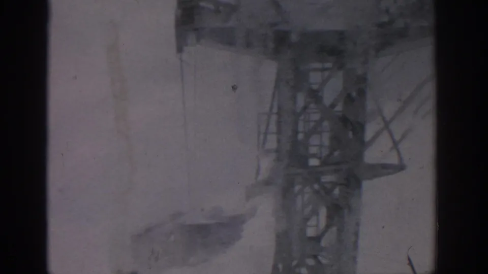 A steel cable-car tower appears beyond a dark interior frame, with pale winter terrain below in 1963 Germany footage.