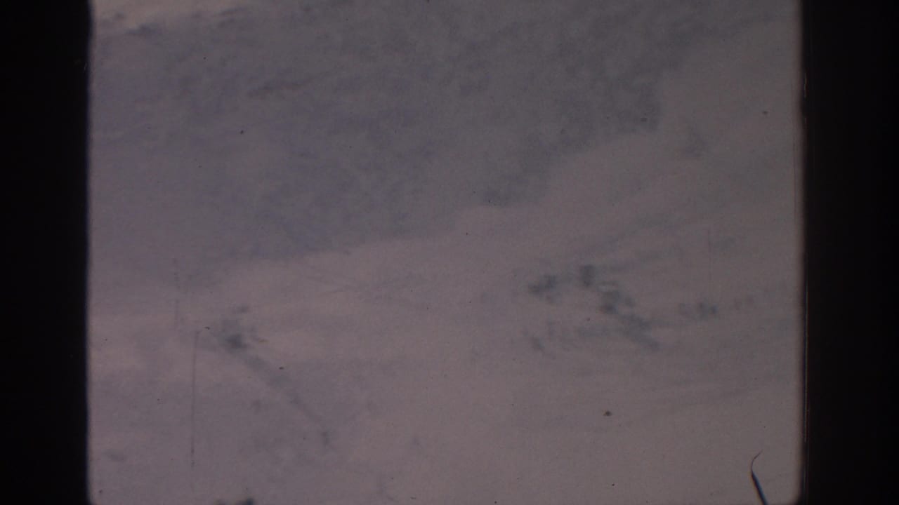 Blurry pale snow-covered area with dark film edge and specks.