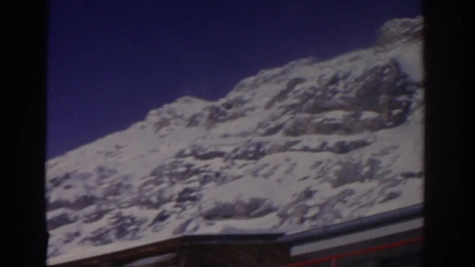 1963 Munich, Germany home-movie frame shifting to a snowy rocky mountain slope and blue sky from the lift area.