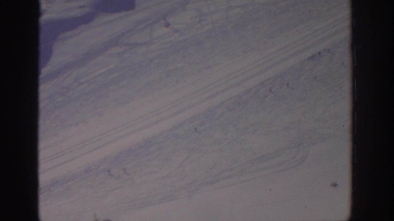 Aerial view of pale ground with diagonal streaks and dark patches near the edge.