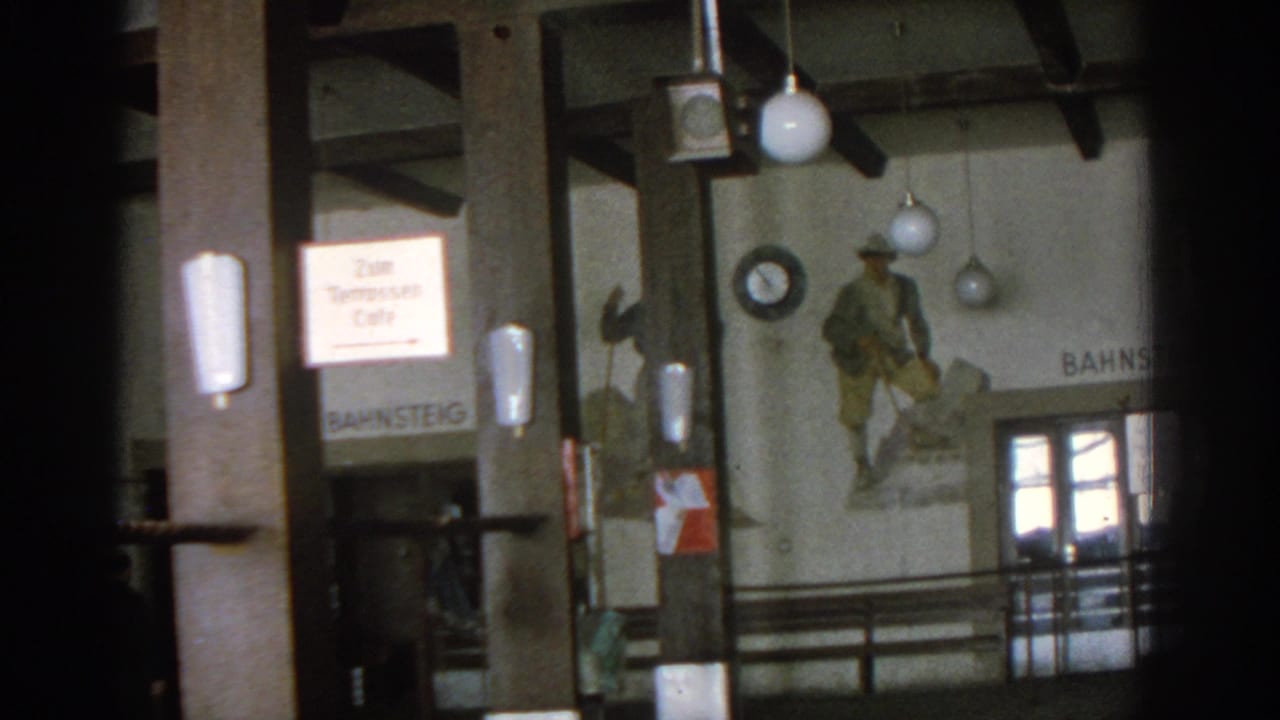 Similar interior view with cafe sign, mural figure, globe lamps, railings, and doors.