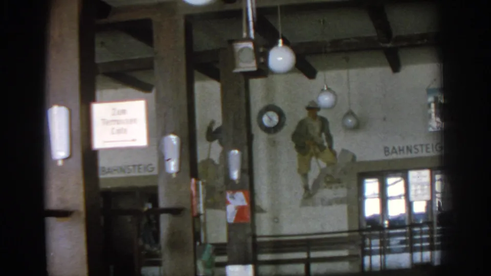 1963 Munich interior view with Zum Tennessee Cafe signage, a painted wall figure, globe lamps, timber structure, and Bahnsteig lettering.