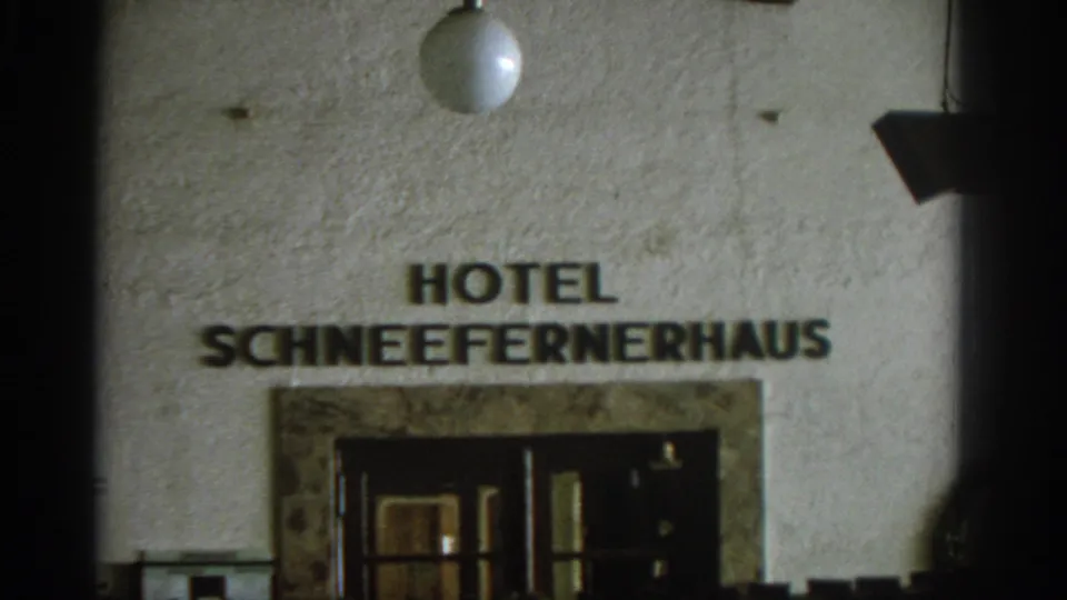 1963 8mm frame showing Hotel Schneefernerhaus name lettering over an entrance, with a round wall light above.