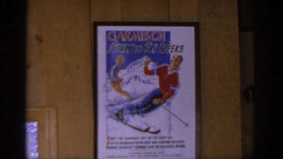 The framed Garmisch Learn to Ski Weeks poster fills the view against a wood-paneled interior wall in the resort setting.