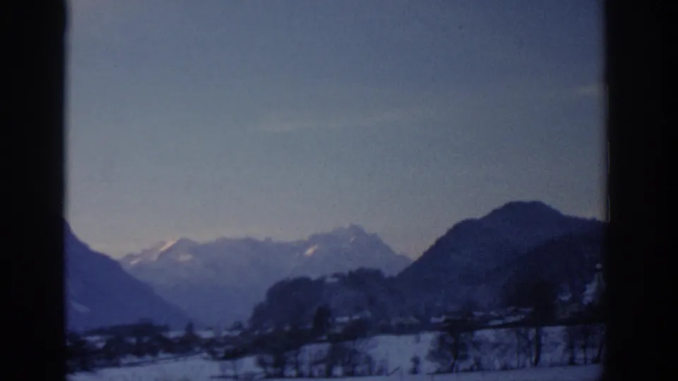 1963 8mm winter landscape near Munich with snow fields, leafless trees and distant mountain peaks.