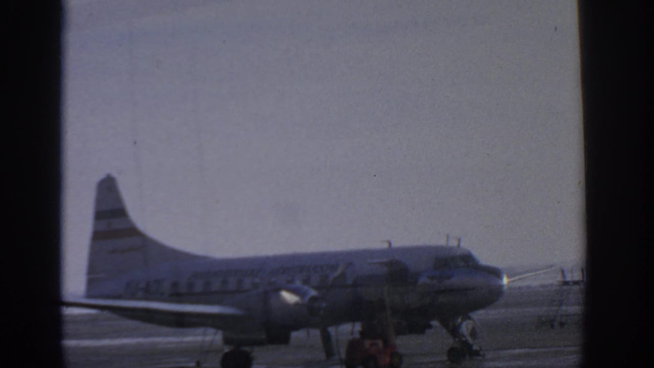 Propeller passenger airplane seen through airport window framing on a tarmac.