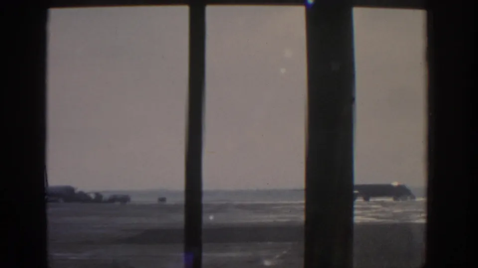 Final 1963 Munich airport view shows a broad apron, distant aircraft, and dark interior window framing.