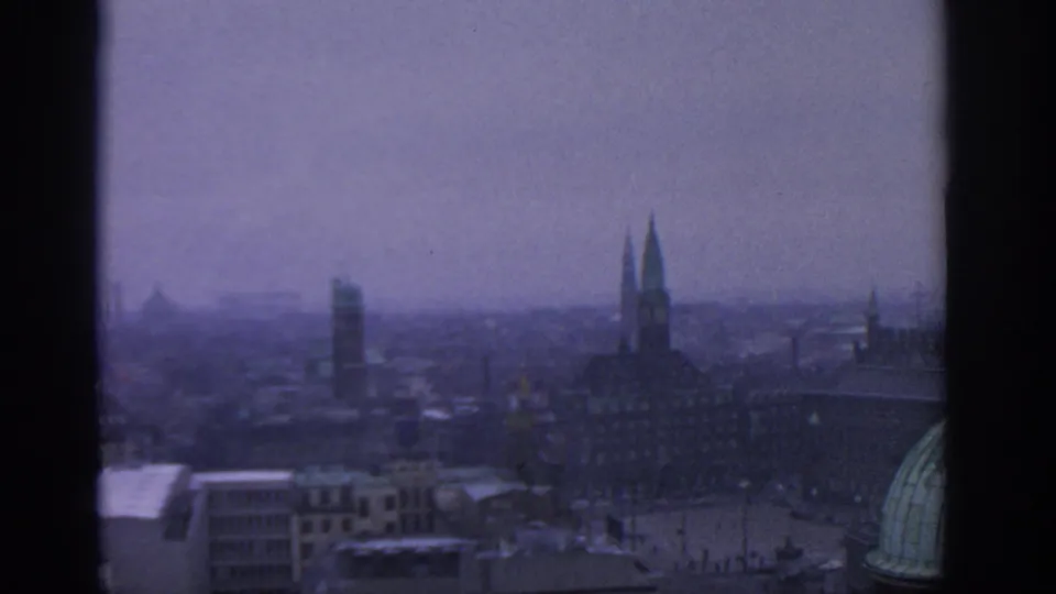 1963 Munich skyline view with historic spires and rooftops softened by haze and 8mm color shift.
