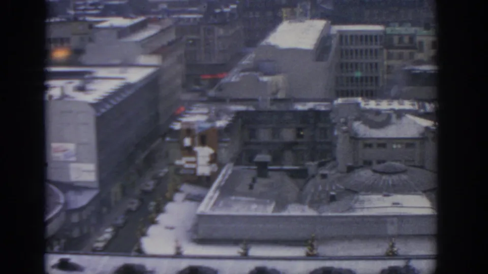1963 Warsaw city view with a domed or circular-roof structure, snow-covered rooftops, street traffic traces, and surrounding mid-century buildings.