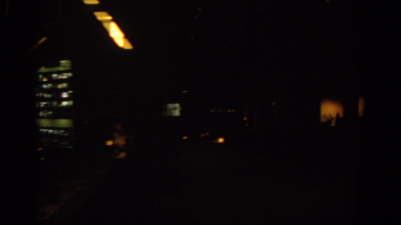 Very dark interior with faint ceiling lights and small illuminated windows.