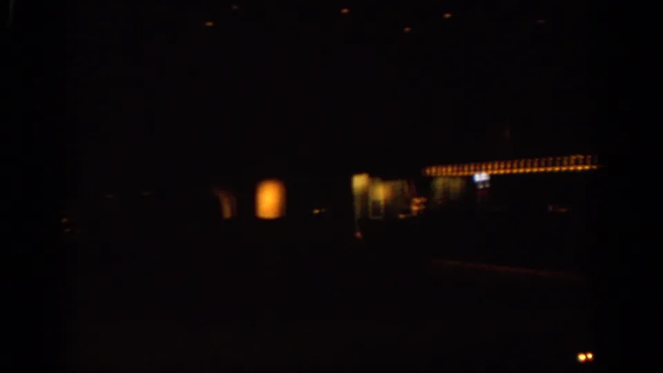 Dim final frame from the 1963 Warsaw clip, showing a dark interior or night transit view with a horizontal row of lights.