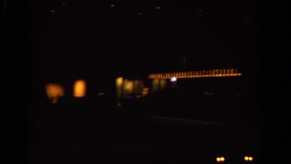1963 Warsaw night footage showing warm illuminated windows or signage against a very dark street scene from a moving viewpoint.