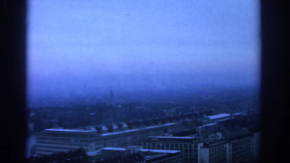 A hazy blue-tinted Warsaw city view appears after the night footage, with rooftops and larger urban buildings visible in soft focus.