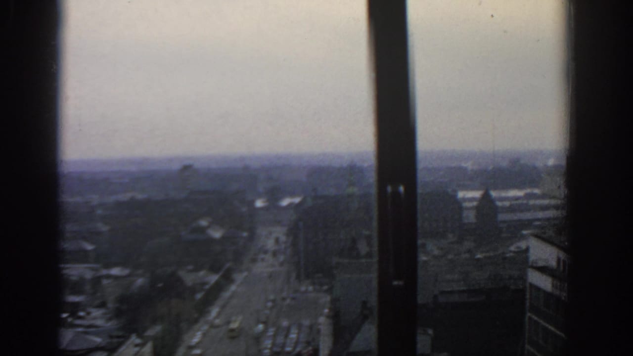 Elevated view of a broad city street through dark window frames.