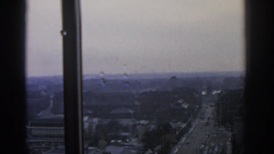 1963 Warsaw urban traffic scene seen from above, with buildings and roads softened by 8mm grain.