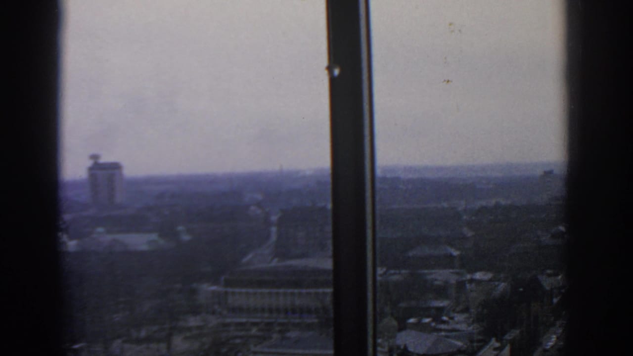 Distant tower and city streets viewed through vertical window frames.
