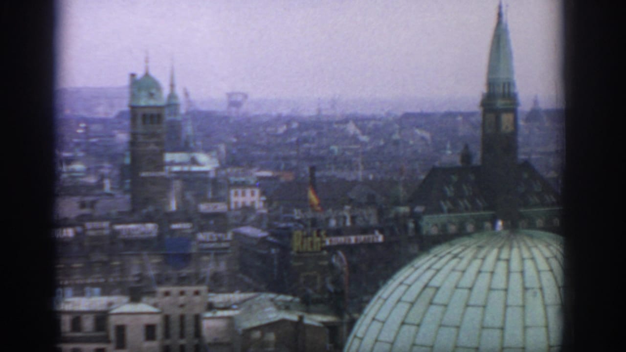Hazy city skyline with church-like towers, a green dome, and dark vertical window framing.