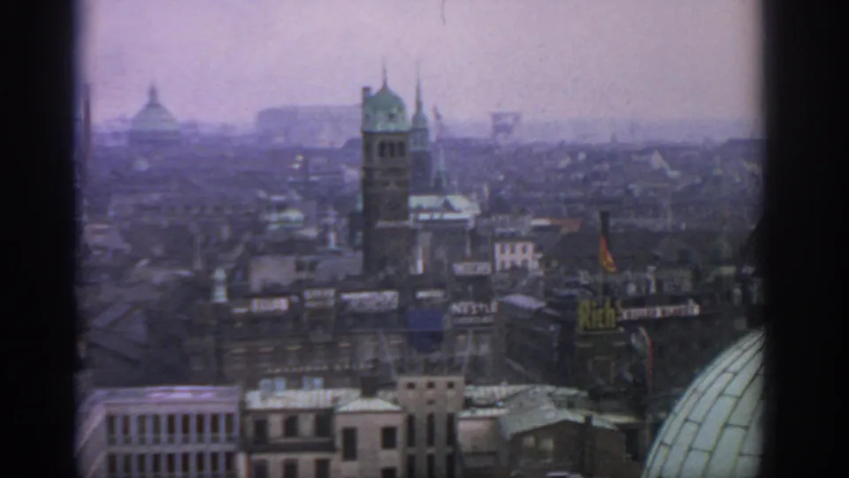 1963 Warsaw skyline frame with a central tower, layered rooftops, signage, and a green dome at the right edge.