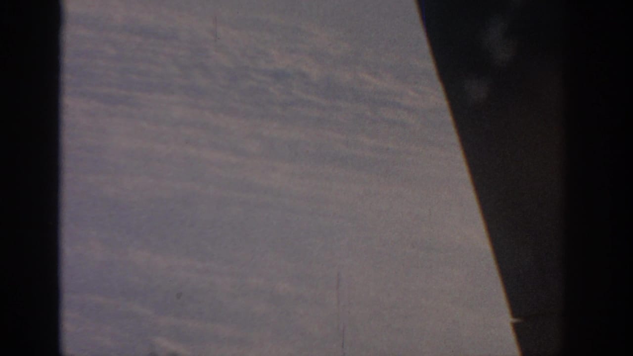 Cloud layer below with a dark vertical aircraft edge and wing surface crossing the frame.