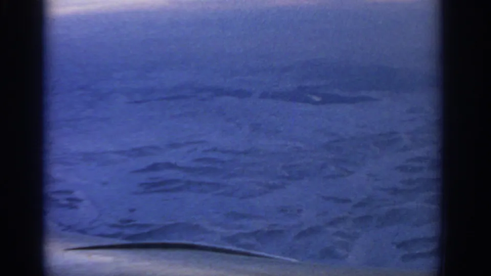 Final frame of the 1963 airplane-window view, showing a blue-tinted snowy landscape without visible landmarks or people.