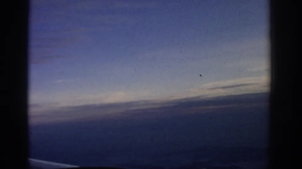 The 8mm frame shows an oblique aerial view at dusk, with the aircraft edge visible below and the horizon crossing the distance.
