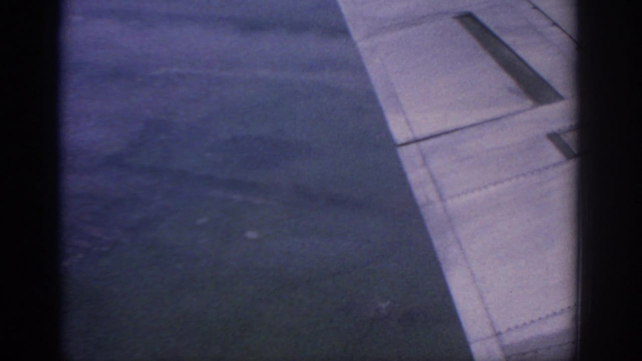 Aircraft wing and dark cloudy view outside the window, with soft grain and low light.