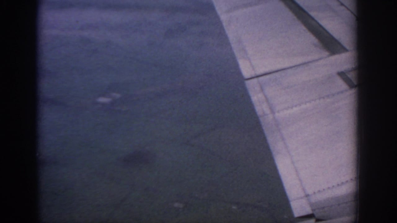 Airplane wing seen from a passenger window with flap and panel detail visible.