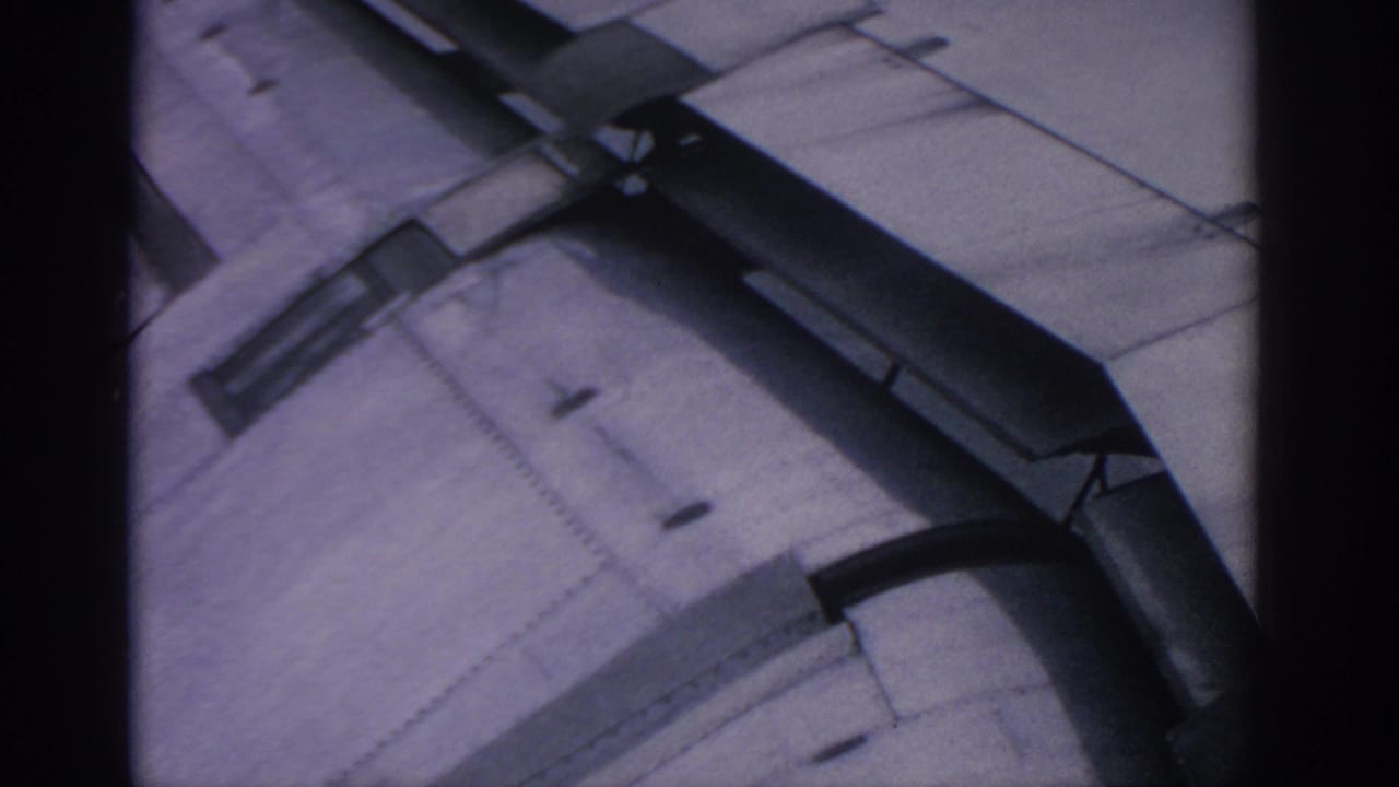Close view of an airplane wing with flap structure and metal panels in soft focus.