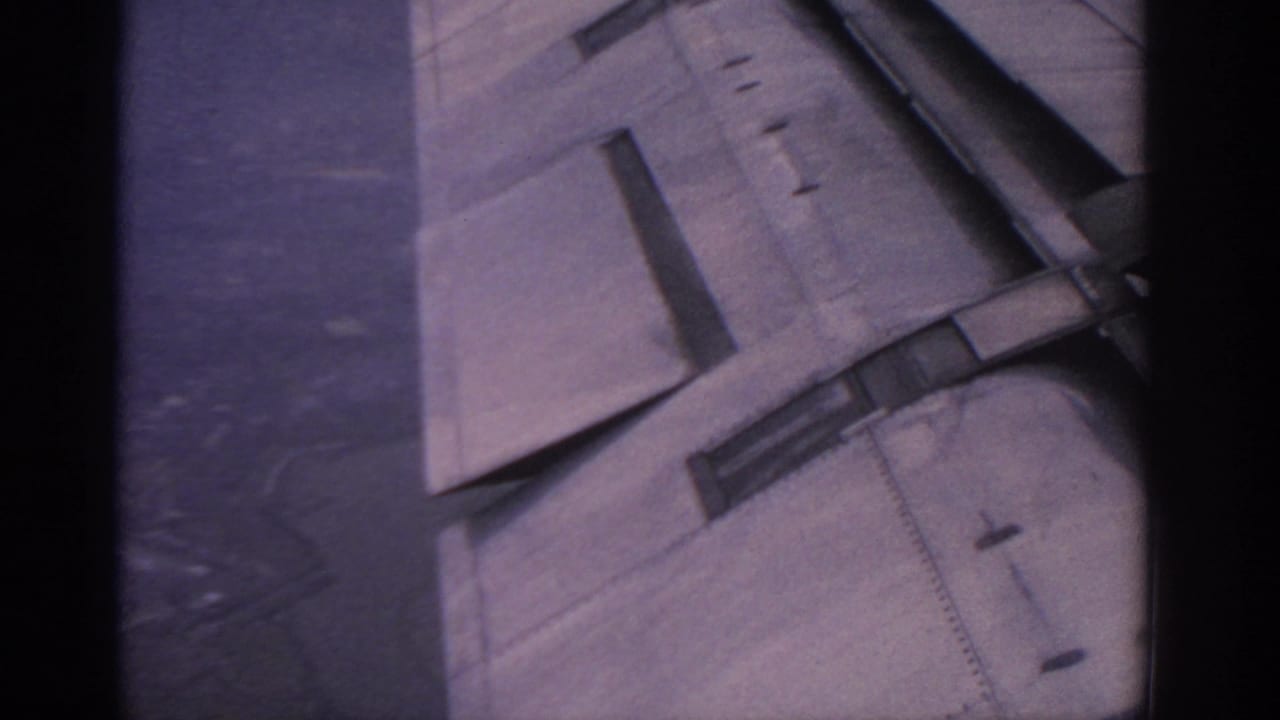 Aircraft wing and flap area seen through a dark airplane window edge.