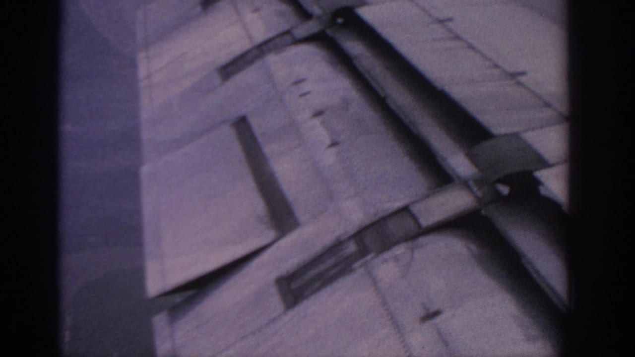 Close passenger-window view of an airplane wing with flap components visible.