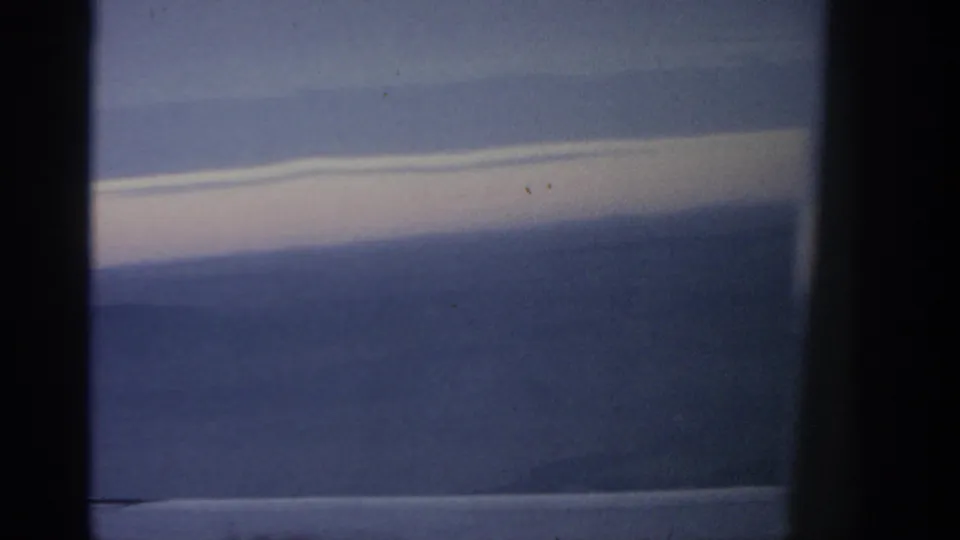 Warsaw-attributed 1963 home-movie frame showing a distant hazy landscape under a bright, narrow cloud band.
