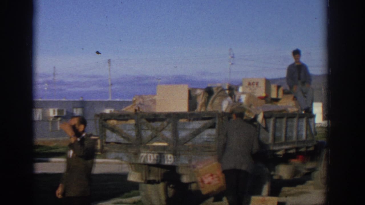 Men around a loaded wooden flatbed truck with cardboard boxes and bags.